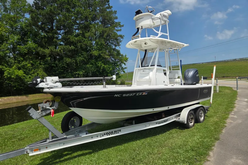 Slide: The Image of 2015 Sea Hunt BX 22 BR boat on trailer, parked on grass, with trees in background. - 1