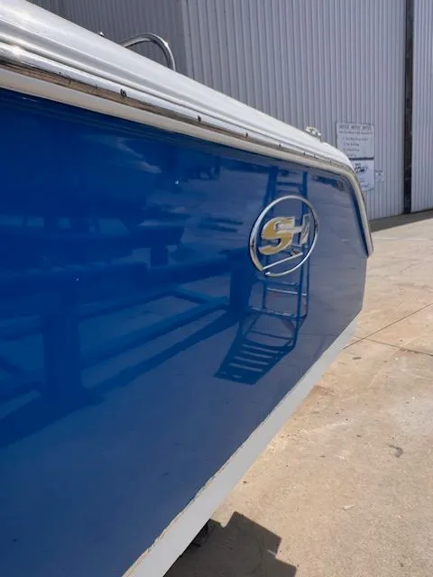 Slide: The Image of Close-up of the blue side of a Sea Hunt 234 SXS boat, positioned on land. - 8