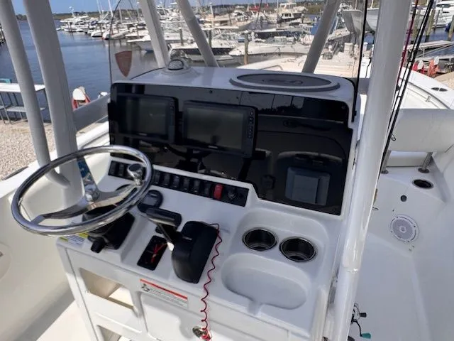 Slide: The Image of The image shows the helm of a Sea Hunt 234 SXS boat docked at a marina. - 19