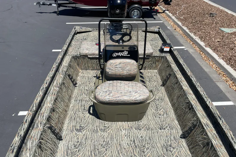 Slide: The Image of 2026 Tracker Grizzly 1860 CC boat with camouflage seating and flooring, parked outdoors. - 9