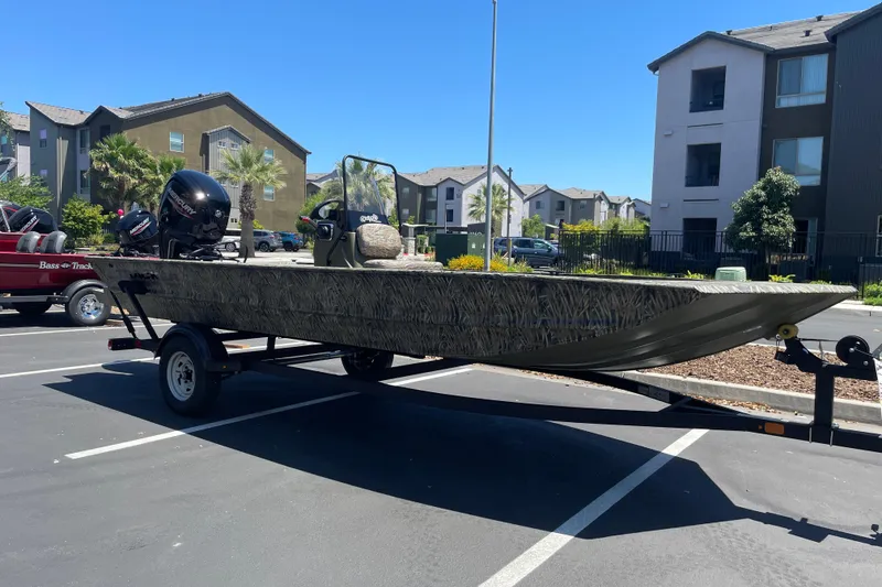 Slide: The Image of 2026 Tracker Grizzly 1860 CC boat on trailer in parking lot, residential buildings in background. - 2