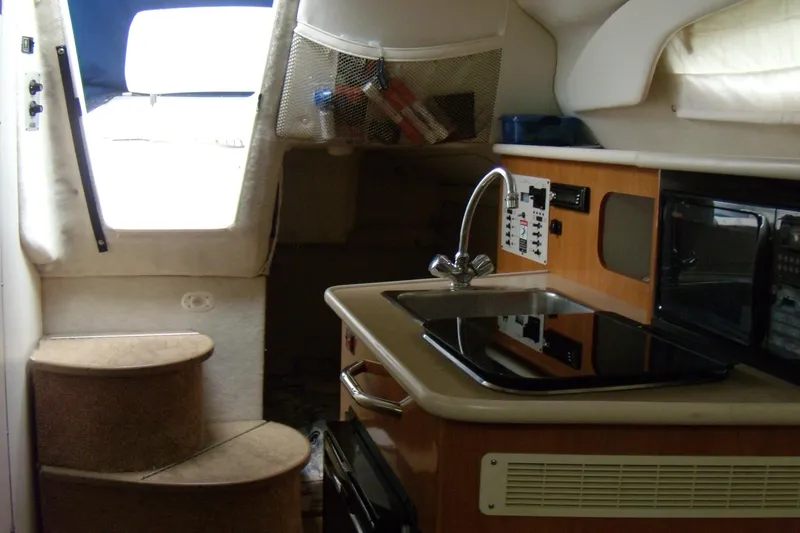 Slide: The Image of Interior of a 2002 Bayliner 2455 Ciera boat featuring a compact kitchen area. - 2
