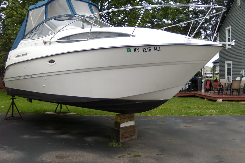 Slide: The Image of 2002 Bayliner 2455 Ciera boat on stands, parked outdoors near a house. - 1