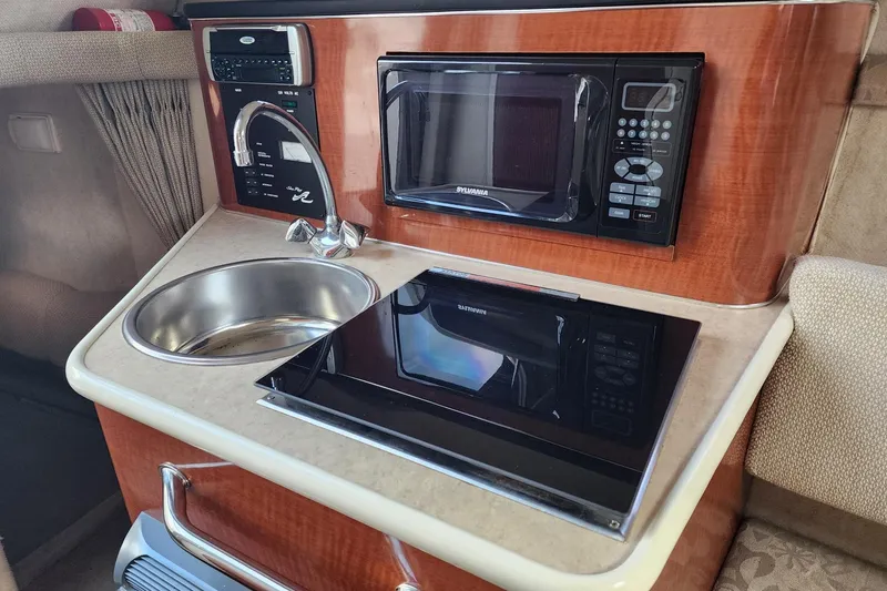 Slide: The Image of Compact kitchenette in a 2003 Sea Ray 240 Sundancer boat with sink, stove, and microwave. - 16