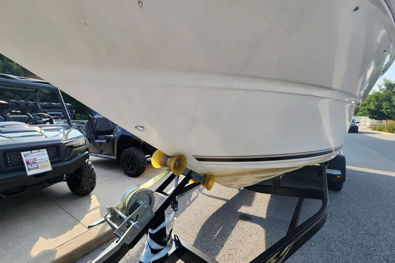 Slide: The Image of 2003 Sea Ray 240 Sundancer boat on trailer, parked beside off-road vehicles. - 11