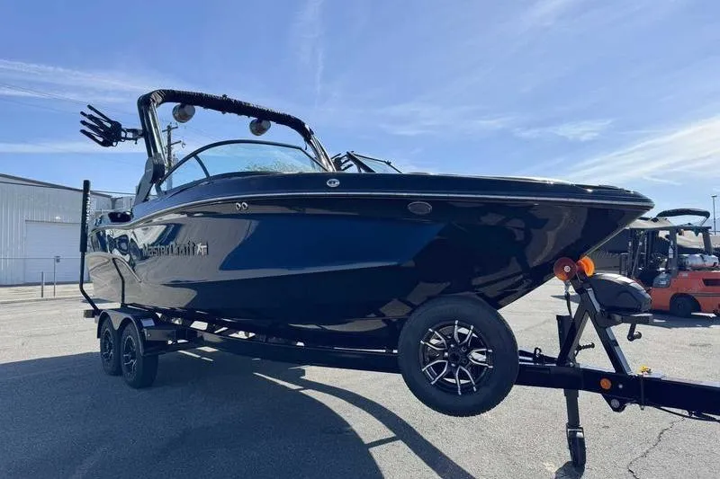 Slide: The Image of 2026 MasterCraft XT23 boat on trailer under clear blue sky. - 2