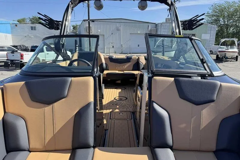 Slide: The Image of 2026 MasterCraft XT23 boat interior with tan and gray seating, open cockpit view. - 13