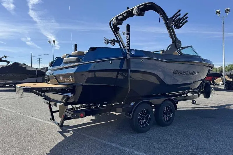 Slide: The Image of 2026 MasterCraft XT23 boat on trailer, parked outdoors under clear sky. - 6