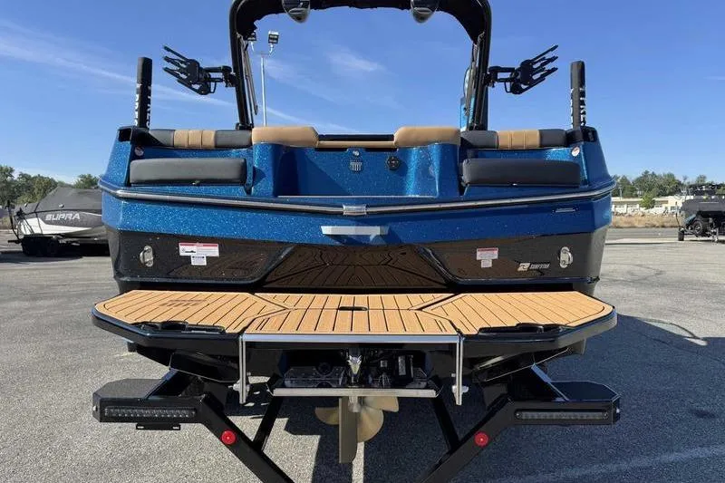 Slide: The Image of 2026 MasterCraft XT23 boat rear view with blue finish and teak swim platform. - 14