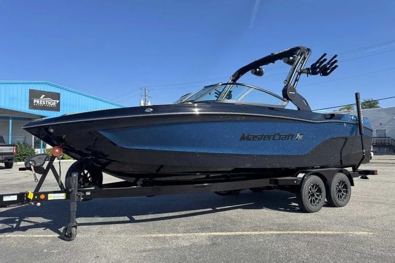 Slide: The Image of 2026 MasterCraft XT23 boat on trailer, parked outside Prestige dealership. - 1