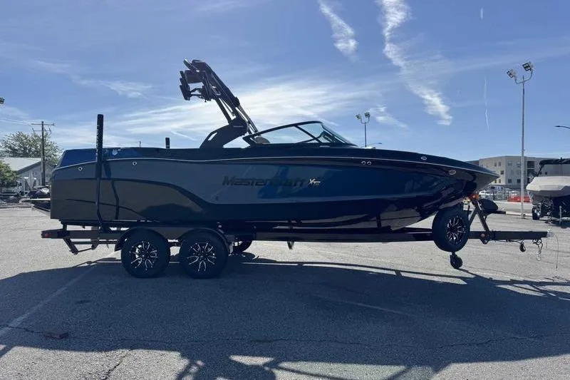 Slide: The Image of 2026 MasterCraft XT23 boat on trailer in parking lot under clear sky. - 4
