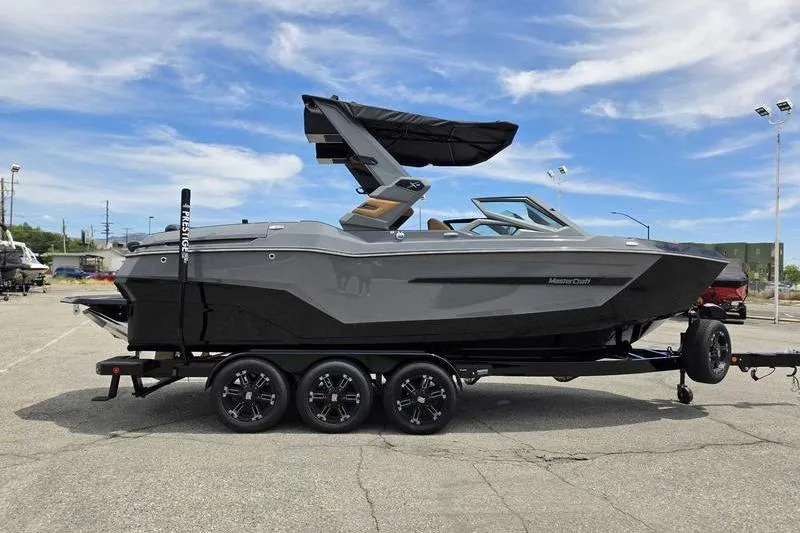 Slide: The Image of 2027 MasterCraft X23 boat on trailer, sleek design, gray exterior, parked outdoors. - 10