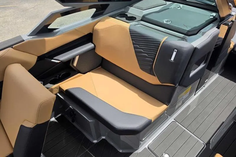 Slide: The Image of 2027 MasterCraft X23 boat interior with tan and gray seating, modern design, and cup holders. - 3