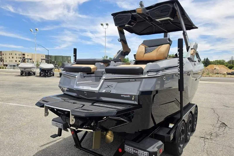 Slide: The Image of 2027 MasterCraft X23 boat on trailer in parking lot, showcasing sleek design and luxury features. - 13