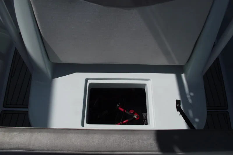 Slide: The Image of 2018 Caravell Key Largo 2486WI boat storage compartment with battery cables visible. - 13