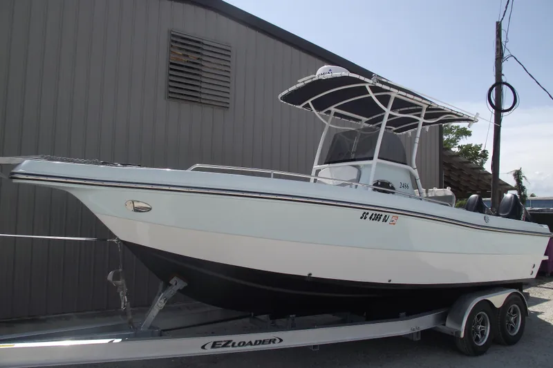 Slide: The Image of 2018 Caravell Key Largo 2486WI boat on trailer, parked beside a building. - 1