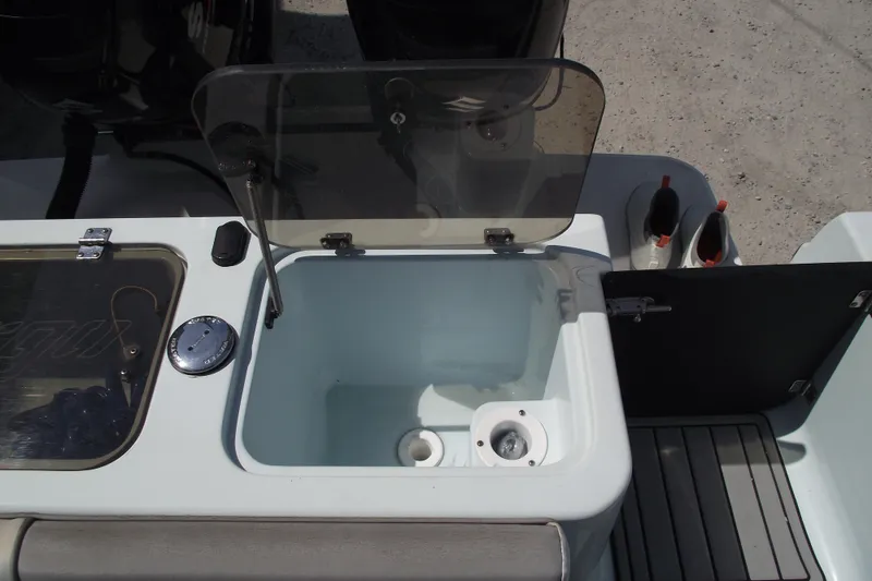 Slide: The Image of 2018 Caravell Key Largo 2486WI boat interior with open storage compartment and fishing rod holders. - 23