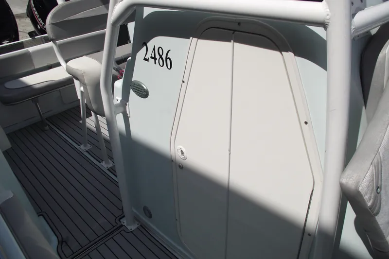 Slide: The Image of 2018 Caravell Key Largo 2486WI boat interior with seating and cabin door. - 10
