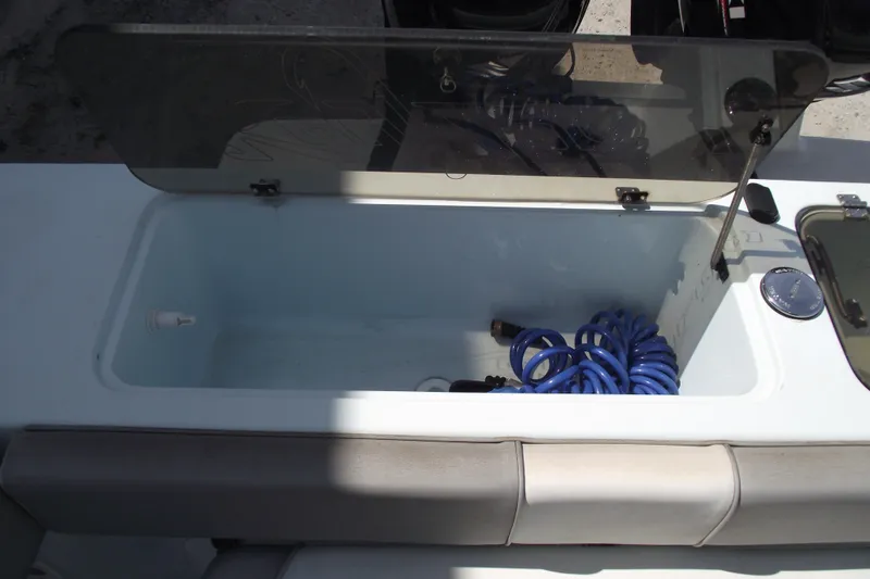 Slide: The Image of 2018 Caravell Key Largo 2486WI boat storage compartment with coiled blue hose. - 24