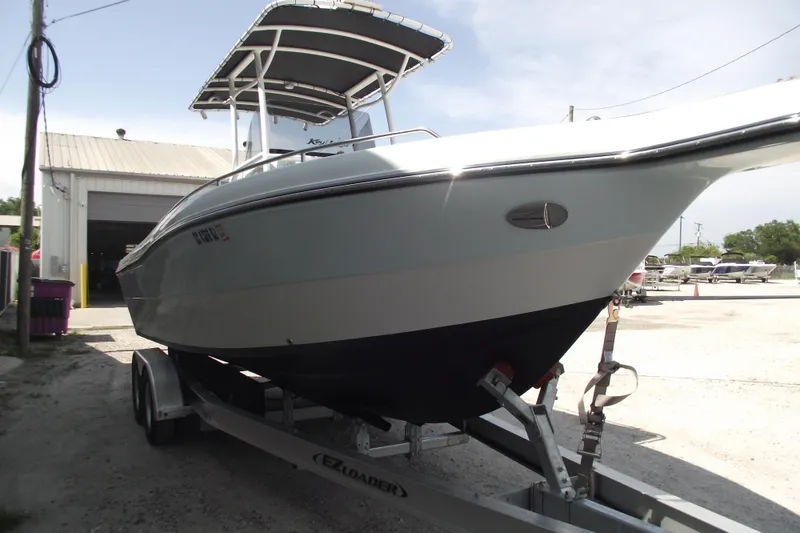 Slide: The Image of 2018 Caravell Key Largo 2486WI boat on trailer, parked outside a garage. - 2