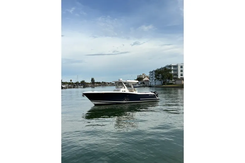 Slide: The Image of 2015 Belzona 32 Center Console boat on calm water near waterfront buildings. - 3