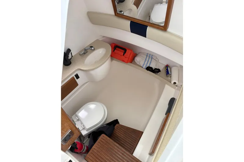 Slide: The Image of Interior of 2015 Belzona 32 Center Console boat, featuring a compact bathroom with sink and toilet. - 6