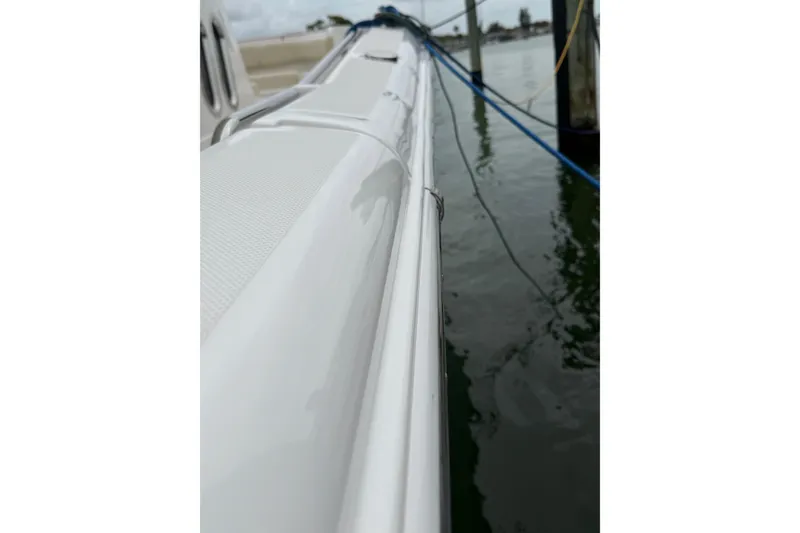 Slide: The Image of 2015 Belzona 32 Center Console boat docked, showcasing sleek white exterior and water reflection. - 13