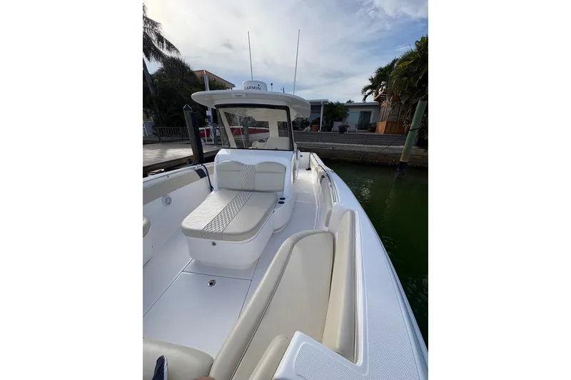 Slide: The Image of 2015 Belzona 32 Cuddy boat with cushioned seating, docked near palm trees. - 9