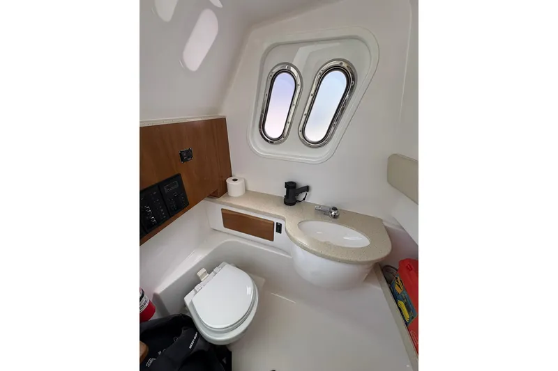 Slide: The Image of Interior of 2015 Belzona 32 Center Console boat featuring a compact bathroom with sink and toilet. - 8