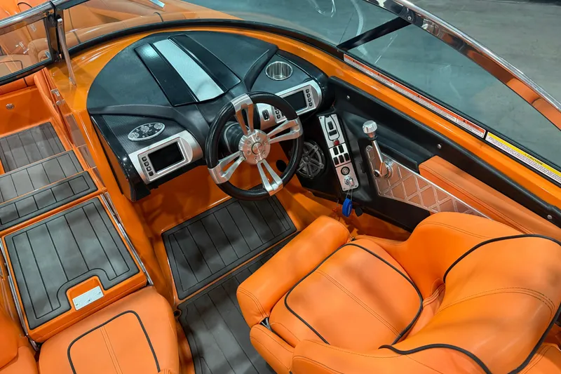 Slide: The Image of 2013 MasterCraft XStar boat interior with orange seats and modern dashboard. - 9