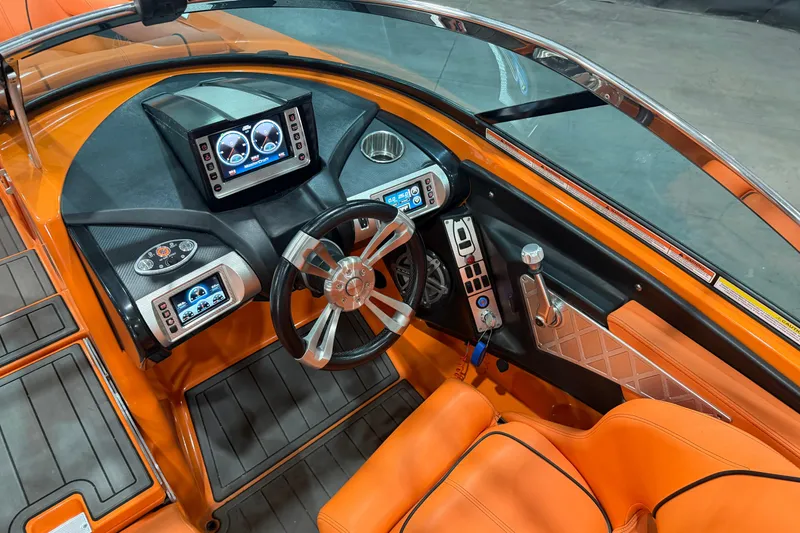 Slide: The Image of 2013 MasterCraft XStar boat interior with orange upholstery and advanced dashboard controls. - 10