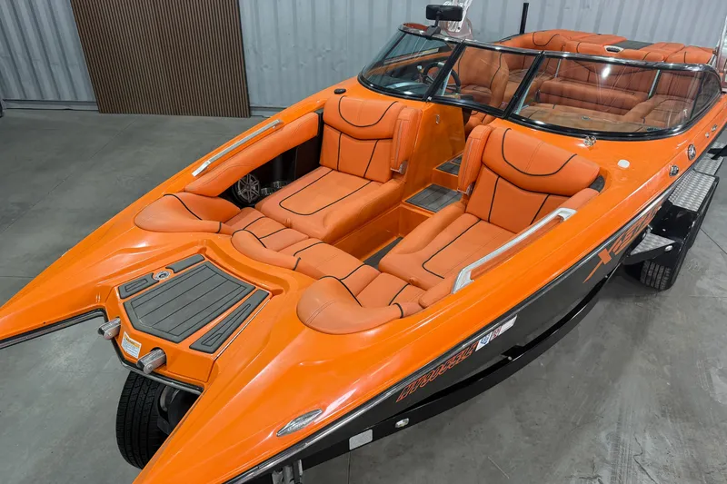 Slide: The Image of 2013 MasterCraft XStar boat with orange seating and sleek design in a showroom. - 4