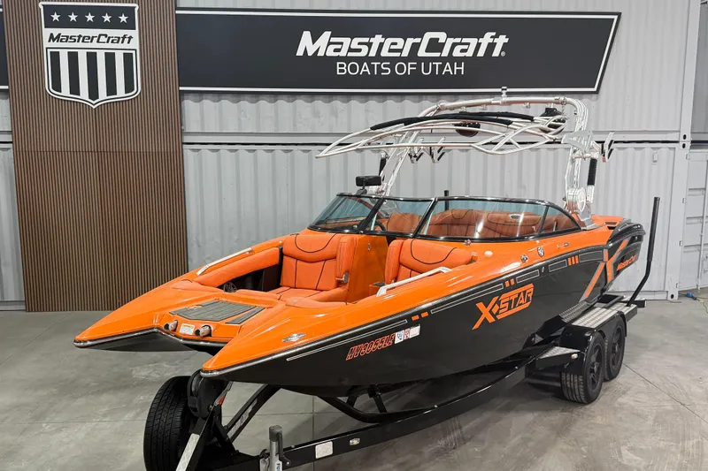 Slide: The Image of 2013 MasterCraft XStar boat in showroom, orange and black design, displayed at MasterCraft Boats of Utah. - 1