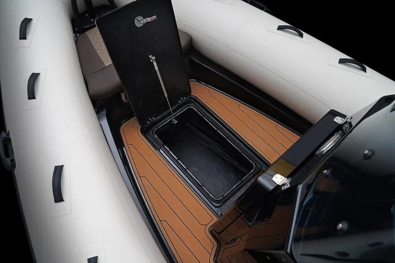 Slide: The Image of 2027 Brig Navigator 22 boat interior with open storage compartment and cushioned seating. - 9