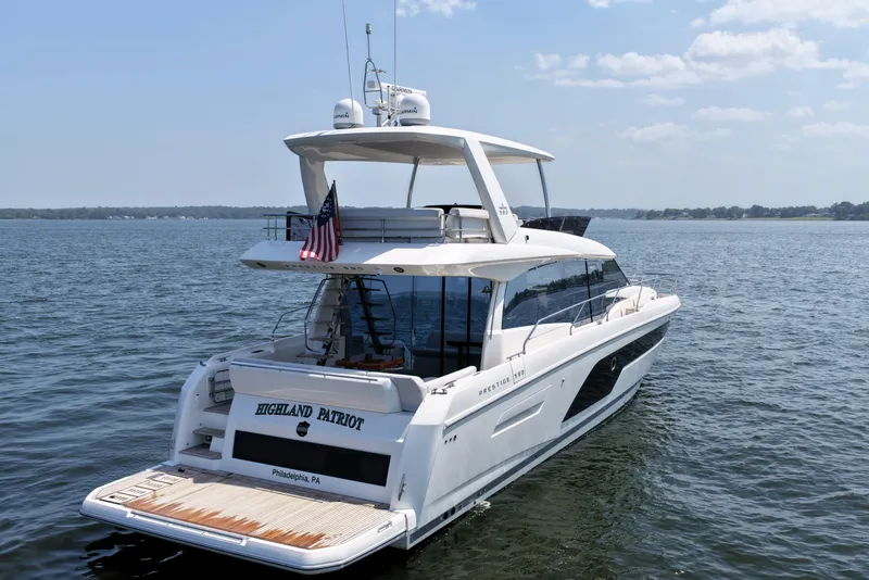Slide: The Image of Luxury 2023 Prestige 590 yacht on serene water, featuring sleek design and American flag. - 8