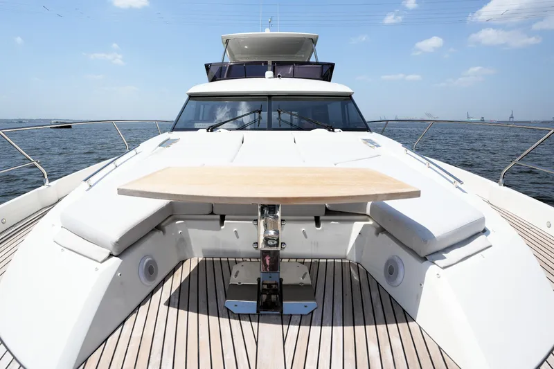 Slide: The Image of Prestige 590 yacht deck with table, 2023 model, on open water under blue sky. - 28