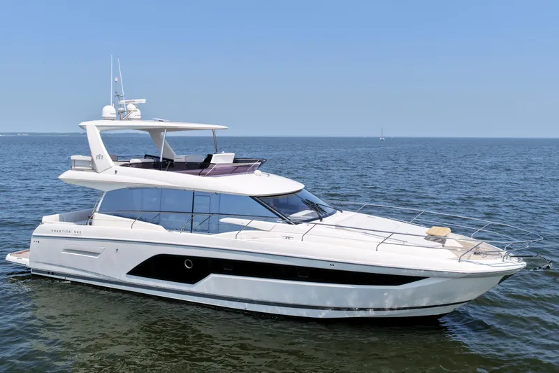 Slide: The Image of Luxury 2023 Prestige 590 yacht cruising on open water under clear blue sky. - 5
