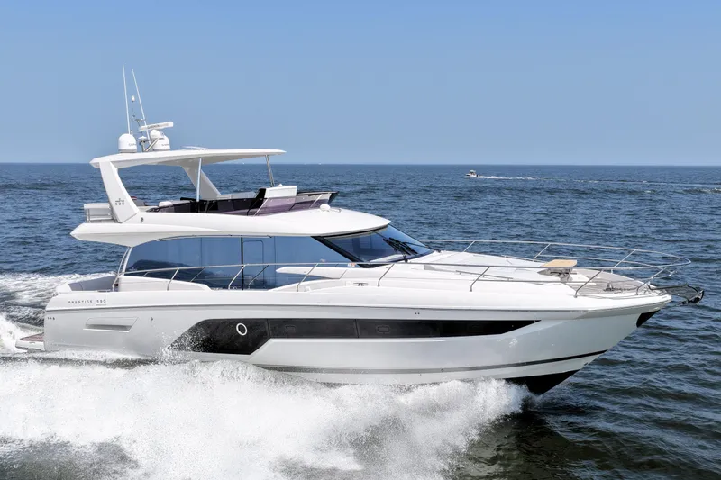 Slide: The Image of Luxury 2023 Prestige 590 yacht cruising on open sea under clear blue sky. - 11