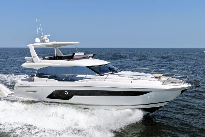 Slide: The Image of Luxury 2023 Prestige 590 yacht cruising on open water under clear blue skies. - 12