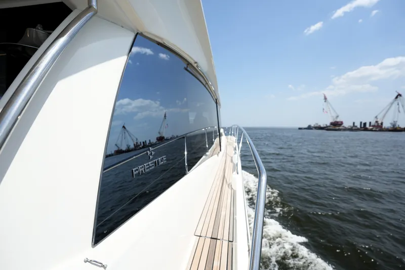 Slide: The Image of Luxury 2023 Prestige 590 yacht cruising on open water under clear blue skies. - 25