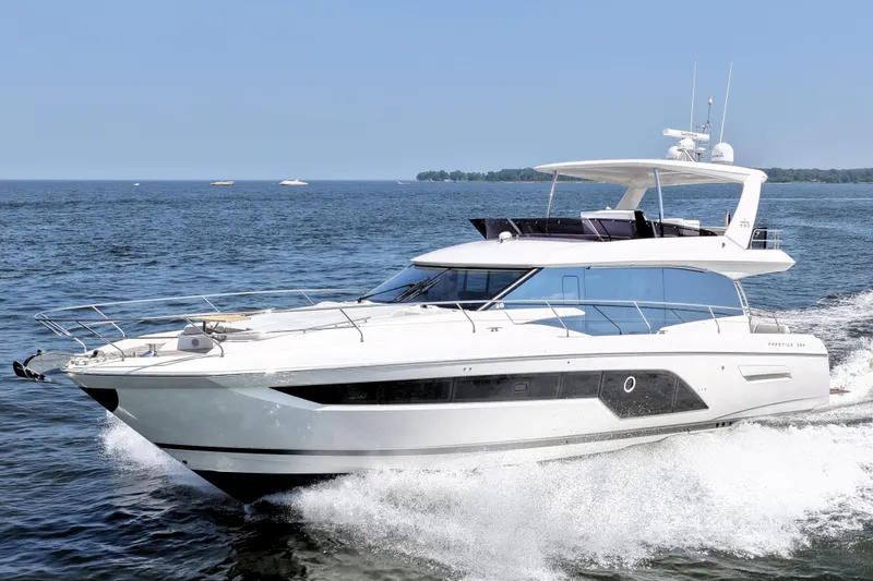 Slide: The Image of 2023 Prestige 590 yacht cruising on open water under clear blue sky. - 14