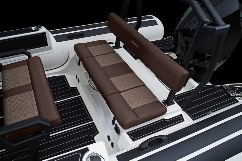 Slide: The Image of 2027 Brig Navigator 24 boat interior with brown quilted seating and sleek black flooring. - 12