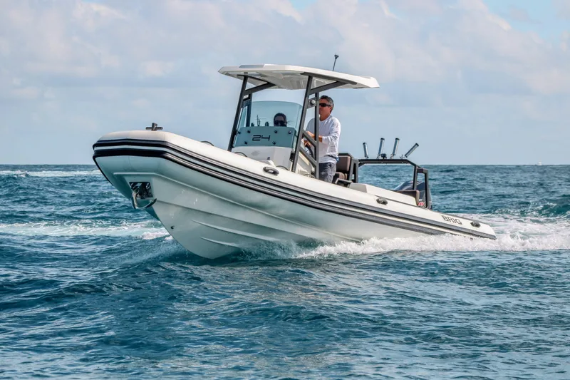 Slide: The Image of 2027 Brig Navigator 24 boat cruising on open water with a person at the helm. - 11