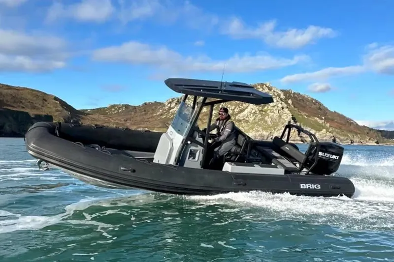 Slide: The Image of Manufacturer Provided Image: 2026 Brig Navigator 24 boat cruising on water with scenic rocky background. - 14