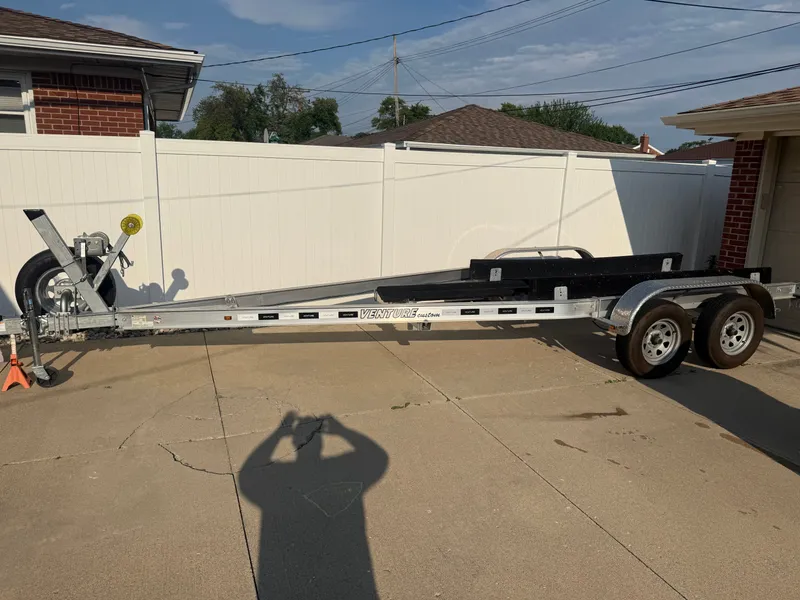 Slide: The Image of A boat trailer is parked on a driveway, surrounded by a white fence and brick buildings. - 29