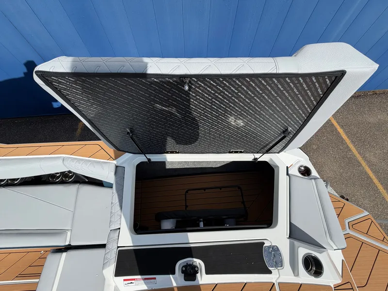 Slide: The Image of The image shows the storage area of a 2027 Nautique S25 Super Air boat with cushioned seating. - 13