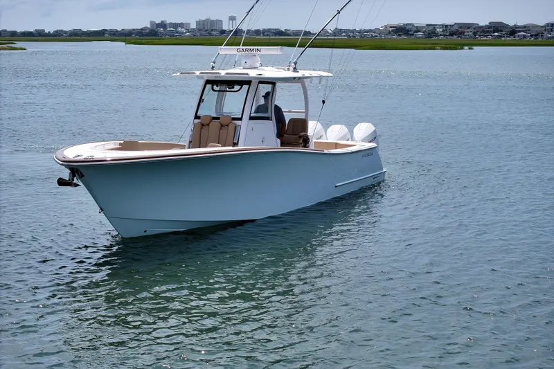 Slide: The Image of 2023 Phenom 34 boat cruising on a calm waterway with cityscape background. - 8