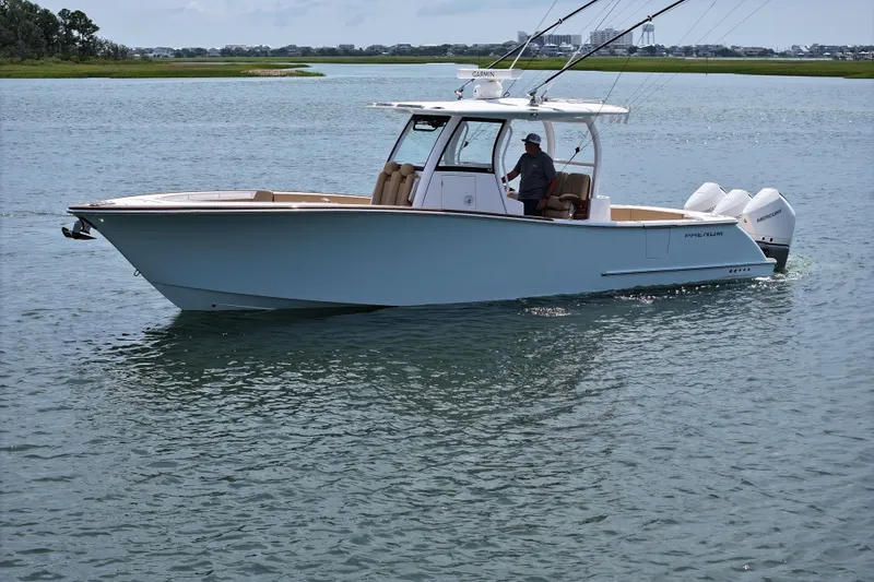 Slide: The Image of 2023 Phenom 34 boat cruising on calm water with scenic background. - 1