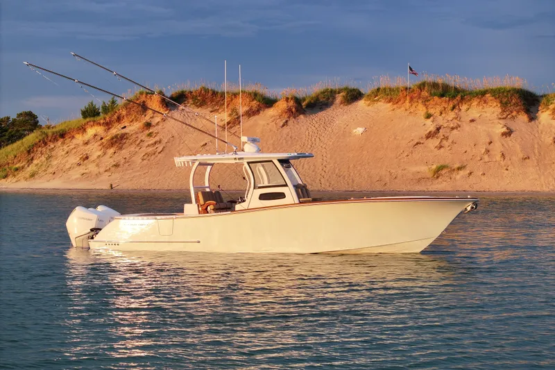 The Image of 2023 Phenom 34 boat on calm water near sandy shoreline. - 0
