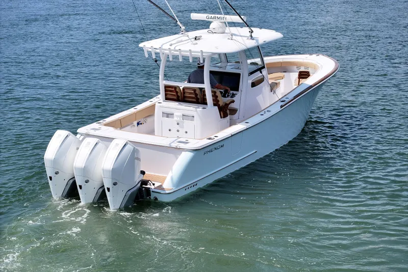 Slide: The Image of 2023 Phenom 34 boat with triple outboard engines cruising on clear water. - 6